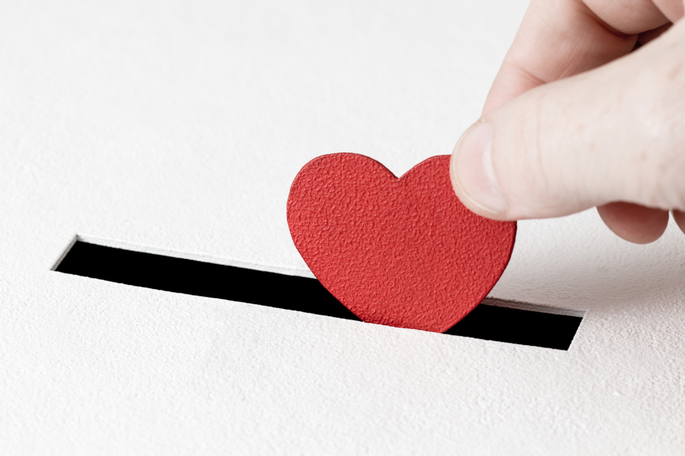 red heart symbol is put by person's hand into slot